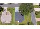 Bird's eye view of a home with dark roof and gray driveway, set amongst green lawns and mature trees in a quiet neighborhood at 670 Fayette Ct, The Villages, FL 32162
