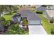 Aerial view highlighting a home's landscaped front yard and hardscape, set amongst lush lawns and mature trees in neighborhood at 670 Fayette Ct, The Villages, FL 32162