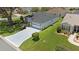Aerial view showcases the home's gray driveway, manicured lawns, mature trees, and pristine exterior within a serene neighborhood at 670 Fayette Ct, The Villages, FL 32162