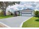 Exterior of a home featuring a two-car garage, a green lawn, and mature shade tree at 670 Fayette Ct, The Villages, FL 32162