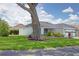 A lush green lawn surrounds this charming white home featuring an attached two car garage at 670 Fayette Ct, The Villages, FL 32162