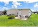 Backyard featuring a small patio with seating surrounded by lush green grass and an American flag at 717 W Coach N Four Dr, Leesburg, FL 34748