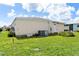 Backyard view with lush grass, minimal landscaping, patio and an air conditioning unit against home at 717 W Coach N Four Dr, Leesburg, FL 34748