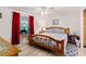 Comfortable bedroom featuring a wood-framed bed, neutral walls, and a connecting sitting area with red curtains at 717 W Coach N Four Dr, Leesburg, FL 34748