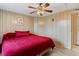 Cozy bedroom with a large window, ceiling fan and red quilted bedspread for a warm and inviting atmosphere at 717 W Coach N Four Dr, Leesburg, FL 34748