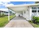 Covered carport featuring a clean concrete floor, adjacent to the home's entrance at 717 W Coach N Four Dr, Leesburg, FL 34748