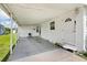 Covered carport area with a clean concrete floor and a white exterior door at 717 W Coach N Four Dr, Leesburg, FL 34748