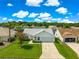 Elevated view of a well-manicured front lawn leading up to a white single-story house in a verdant neighborhood at 804 Santa Rita Way, Lady Lake, FL 32159