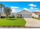 Inviting single-story home featuring a well-kept lawn, a two-car garage, and trimmed hedges under a clear sky at 804 Santa Rita Way, Lady Lake, FL 32159