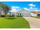 Charming single-story home with a well-maintained lawn, mature tree, and a two-car garage on a sunny day at 804 Santa Rita Way, Lady Lake, FL 32159