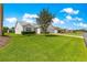 Quaint single-story home with lush front lawn and mature tree providing shade on a sunny day with blue skies at 804 Santa Rita Way, Lady Lake, FL 32159