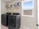 Modern laundry room with front load washer and dryer, wire shelving, and a bright window at 872 Griffon Ave, Lake Alfred, FL 33850