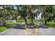 Community entrance with lush trees, manicured landscaping, and community information signage at 10 Cocos Plumosa Dr, Eustis, FL 32726