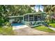 Inviting single-story home featuring a screened-in porch, carport, well-manicured lawn, and tropical landscaping at 10 Cocos Plumosa Dr, Eustis, FL 32726