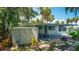 Charming home exterior featuring a covered patio, shed, and lush landscaping at 10 Cocos Plumosa Dr, Eustis, FL 32726