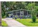 Attractive single-story home boasting a screened-in porch, carport, well-manicured lawn, and tropical landscaping at 10 Cocos Plumosa Dr, Eustis, FL 32726
