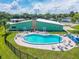 Aerial view of a community pool with a unique stone fireplace and ample deck seating at 10 Cocos Plumosa Dr, Eustis, FL 32726