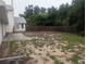Large backyard with a mix of grass and weeds, bordered by a wooden fence and the home's exterior at 11532 Beaman Cir, Clermont, FL 34711