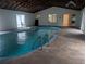 Bright indoor pool area featuring cool blue water, stainless steel handrails, and ample natural light at 11532 Beaman Cir, Clermont, FL 34711