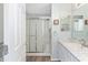 Bright bathroom features a walk-in shower with a sliding glass door, a marble countertop vanity, and light paint at 1334 Hollyberry Pl, The Villages, FL 32162