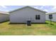 View of the home's exterior showing the siding, window, and air conditioning unit in the well-maintained backyard at 1334 Hollyberry Pl, The Villages, FL 32162