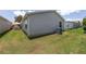 View of the home's exterior showcasing the patio set, siding, window, AC unit, and well-maintained lawn at 1334 Hollyberry Pl, The Villages, FL 32162