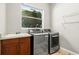 Bright laundry room with modern washer and dryer, overhead storage and a window at 1444 Whitney Isles Dr, Windermere, FL 34786