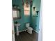 Turquoise bathroom featuring a pedestal sink, toilet, vanity mirror, and modern decor at 149 Roseling Xing, Davenport, FL 33897
