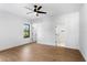 A bright, minimalist bedroom with wood-look flooring, a ceiling fan, and two doors at 16615 Oklahoma St, Clermont, FL 34715