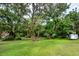 Large parcel of green property featuring mature trees and a metal shed or trailer on the right side of the property at 16615 Oklahoma St, Clermont, FL 34715