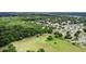 Expansive aerial view showcases property backing up to wooded area near neighborhood amenities and nearby bodies of water at 1702 Hoofprint Ct, Fruitland Park, FL 34731