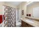 Well-lit bathroom featuring a granite vanity, framed mirror and a tub-shower with a decorative shower curtain at 1702 Hoofprint Ct, Fruitland Park, FL 34731