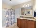 Bathroom with dual sinks and a walk-in shower with blue and white curtain at 1702 Hoofprint Ct, Fruitland Park, FL 34731