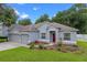 Well-manicured lawn with flower beds highlighting this single-story house with a three-car garage at 1702 Hoofprint Ct, Fruitland Park, FL 34731