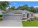 Beautiful single-story home featuring a three-car garage, landscaped yard, and a charming red front door at 1702 Hoofprint Ct, Fruitland Park, FL 34731