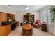 Cozy office with custom wood desk and bookshelves with a comfortable chair and plenty of natural light at 1702 Hoofprint Ct, Fruitland Park, FL 34731