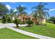 Beautifully landscaped home with an expansive driveway, lush lawn and mature palm trees at 1892 Sanderling Dr, Clermont, FL 34711