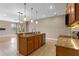 Open-concept kitchen with a granite island, wooden cabinets and access to an adjacent living area at 1892 Sanderling Dr, Clermont, FL 34711