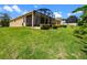 A view of the home's rear exterior featuring a screened-in porch and well-maintained yard at 1892 Sanderling Dr, Clermont, FL 34711