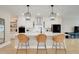Bright kitchen with white cabinets, black appliances, large island with seating, and modern pendant lighting at 2161 Gold Dust Dr, Minneola, FL 34715