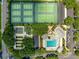 Overhead view of community tennis courts and shuffleboard courts next to pool, parking, and landscaping at 2450 Merida Cir, The Villages, FL 32162