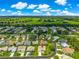 Elevated view showcasing home nestled in a neighborhood with manicured lawns and mature trees under a clear blue sky at 2450 Merida Cir, The Villages, FL 32162