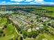 Aerial view of home and neighborhood nestled in golf course community and lush landscaping under blue skies at 2450 Merida Cir, The Villages, FL 32162