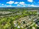 Aerial photo highlighting home in golf course community with mature trees and green space under a blue sky at 2450 Merida Cir, The Villages, FL 32162