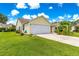 Charming, one-story home featuring a two-car garage, lush lawn, and mature landscaping at 2450 Merida Cir, The Villages, FL 32162