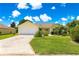 Charming home with a well-manicured lawn, mature trees, and a long driveway leading to a two-car garage at 2450 Merida Cir, The Villages, FL 32162