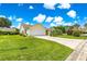 Beautiful yellow home with a lush green lawn, complemented by well-placed landscaping and a concrete driveway at 2450 Merida Cir, The Villages, FL 32162