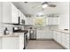 Modern kitchen with white cabinetry, stainless steel appliances, and a herringbone tile backsplash at 2450 Merida Cir, The Villages, FL 32162