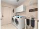Convenient laundry room with washer, dryer, sink, and storage cabinets at 2450 Merida Cir, The Villages, FL 32162