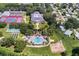 Aerial view of community amenities including pool, clubhouse, tennis courts, shuffleboard courts, and undeveloped land at 25400 Waterbrook Ct, Leesburg, FL 34748